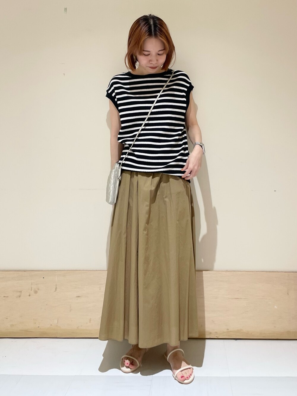 ベージュ系のスカート、ホワイト系のサンダル、ブラック系のTシャツ/カットソーを着用したレディースの夏コーディネートの2枚目の写真