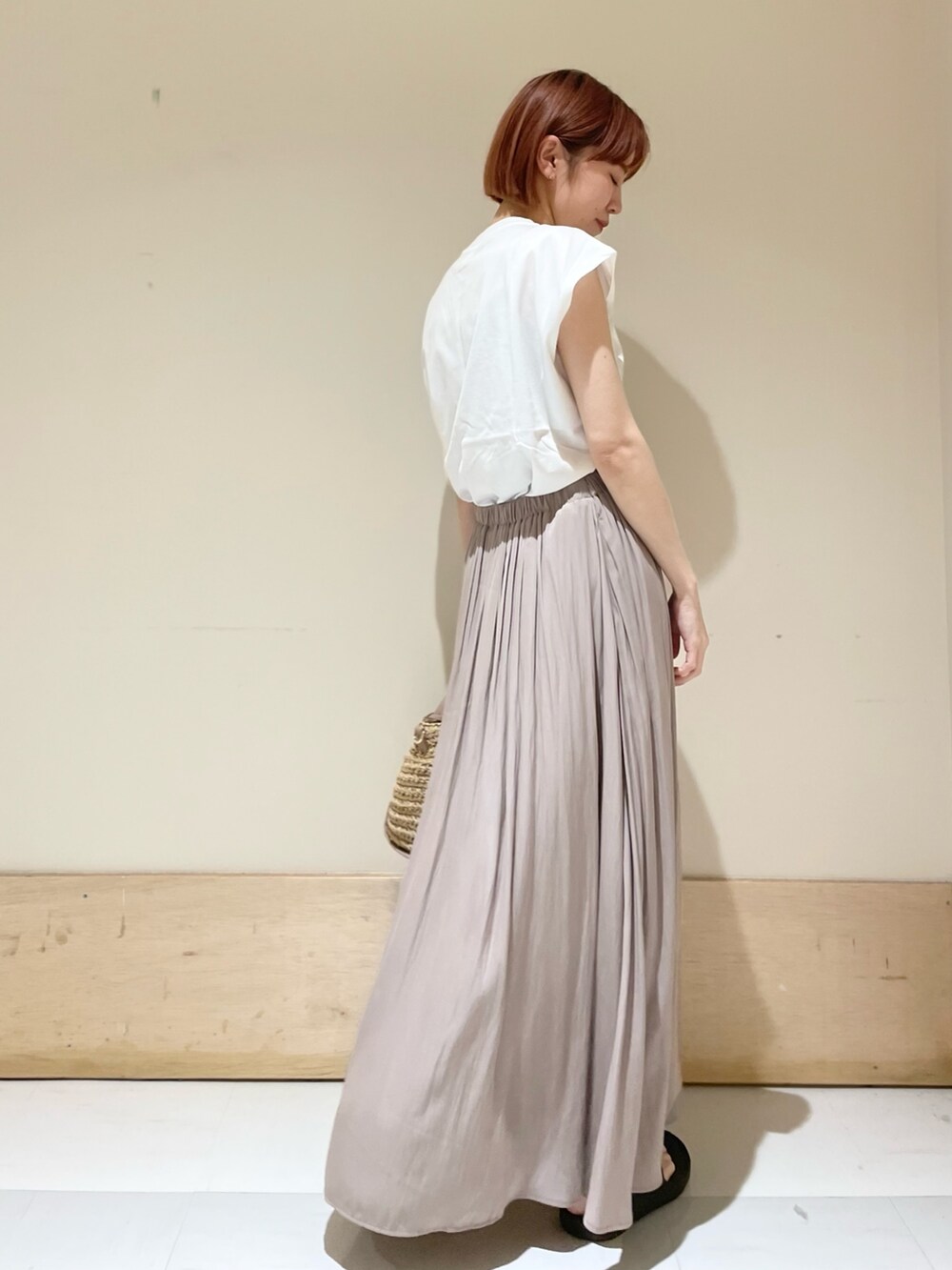 グレー系のスカート、ホワイト系のTシャツ/カットソー、ベージュ系のかごバッグを着用したレディースの春コーディネートの5枚目の写真