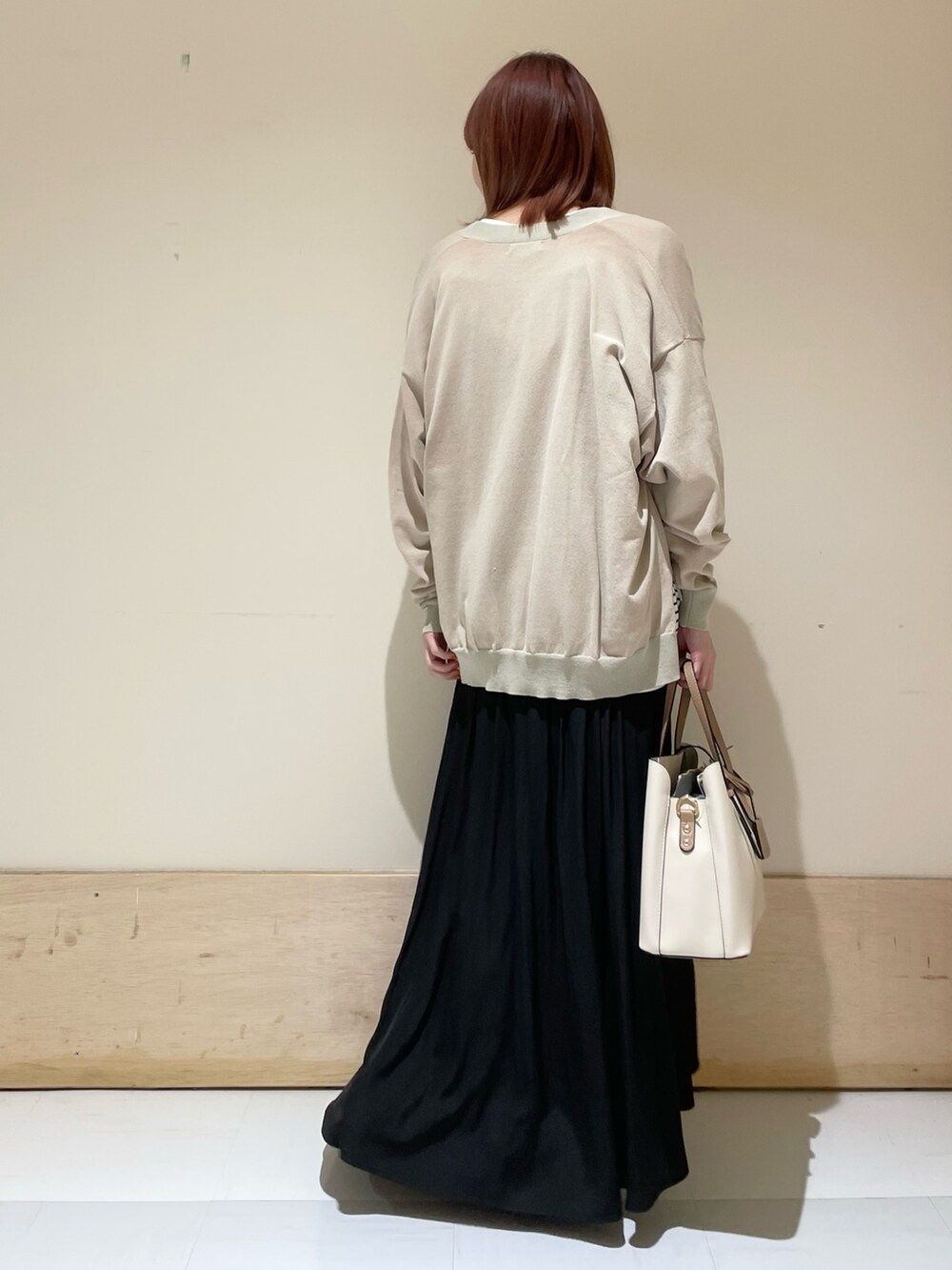ブラック系のスカート、ホワイト系のTシャツ/カットソー、ベージュ系のカーディガン/ボレロを着用したレディースの春コーディネートの6枚目の写真