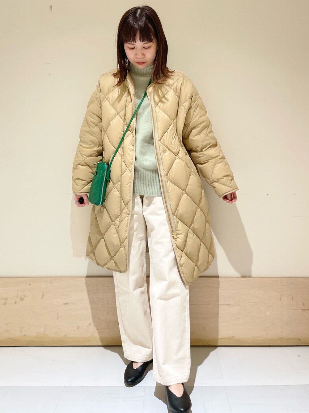 ベージュ系のデニムパンツ、ベージュ系のダウンジャケット/コート、グリーン系のニット/セーターを着用したレディースの冬コーディネートの3枚目の写真