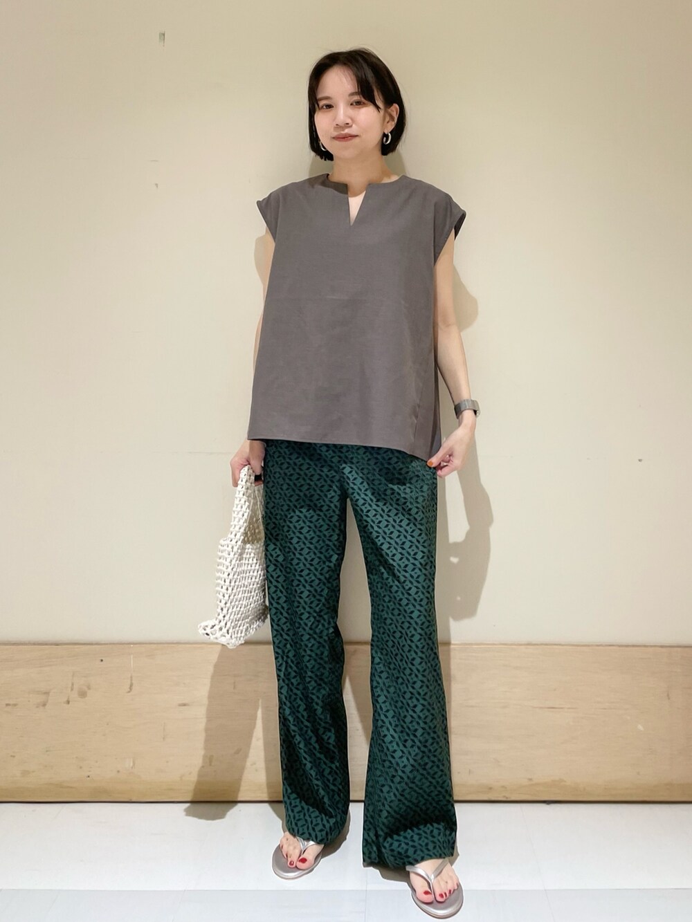 グレー系のシャツ/ブラウス、ホワイト系のハンドバッグ、シルバー系のサンダルを着用したレディースの夏コーディネートの3枚目の写真