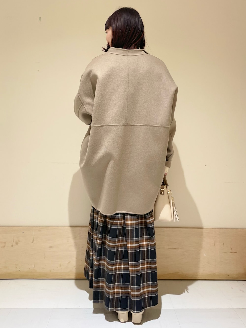 ベージュ系のその他アウター、ホワイト系のニット/セーター、ブラック系のスカートを着用したレディースの冬コーディネートの3枚目の写真