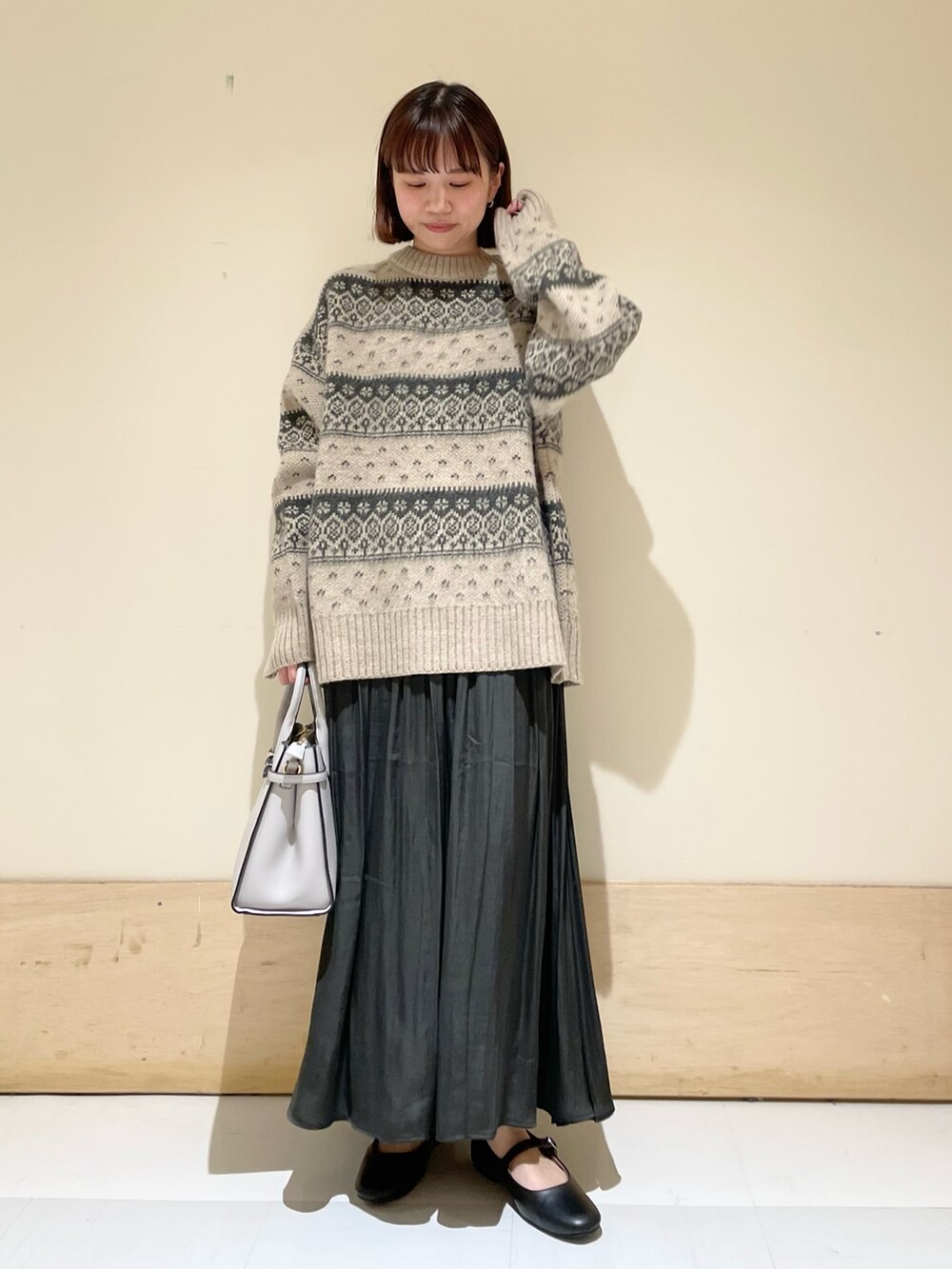 ベージュ系のニット/セーター、グレー系のスカート、ブラック系のその他シューズを着用したレディースの冬コーディネートの2枚目の写真