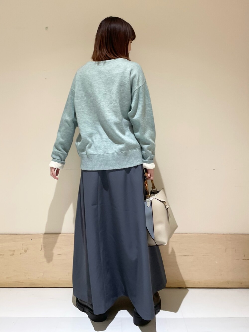 グレー系のスカート、グリーン系のニット/セーターを着用したレディースの冬コーディネートの5枚目の写真