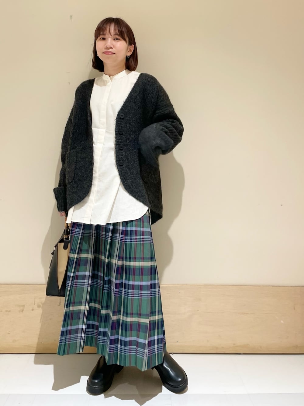 ホワイト系のシャツ/ブラウス、ブラック系のカーディガン/ボレロ、ブラック系のブーツを着用したレディースの秋コーディネートの2枚目の写真