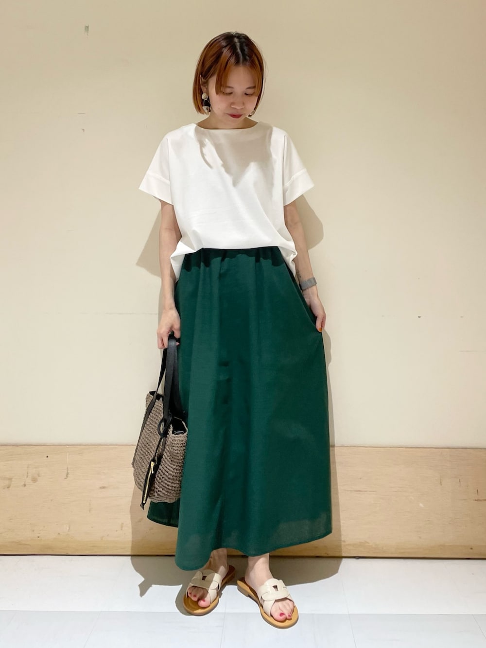 ホワイト系のTシャツ/カットソー、グレー系のトートバッグ、グリーン系のスカートを着用したレディースの夏コーディネートの2枚目の写真