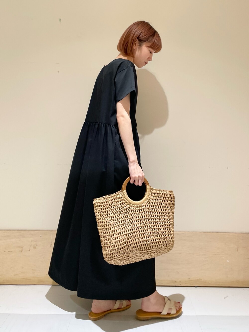 ホワイト系のサンダル、ベージュ系のかごバッグ、ブラック系のワンピースを着用したレディースの春コーディネートの5枚目の写真