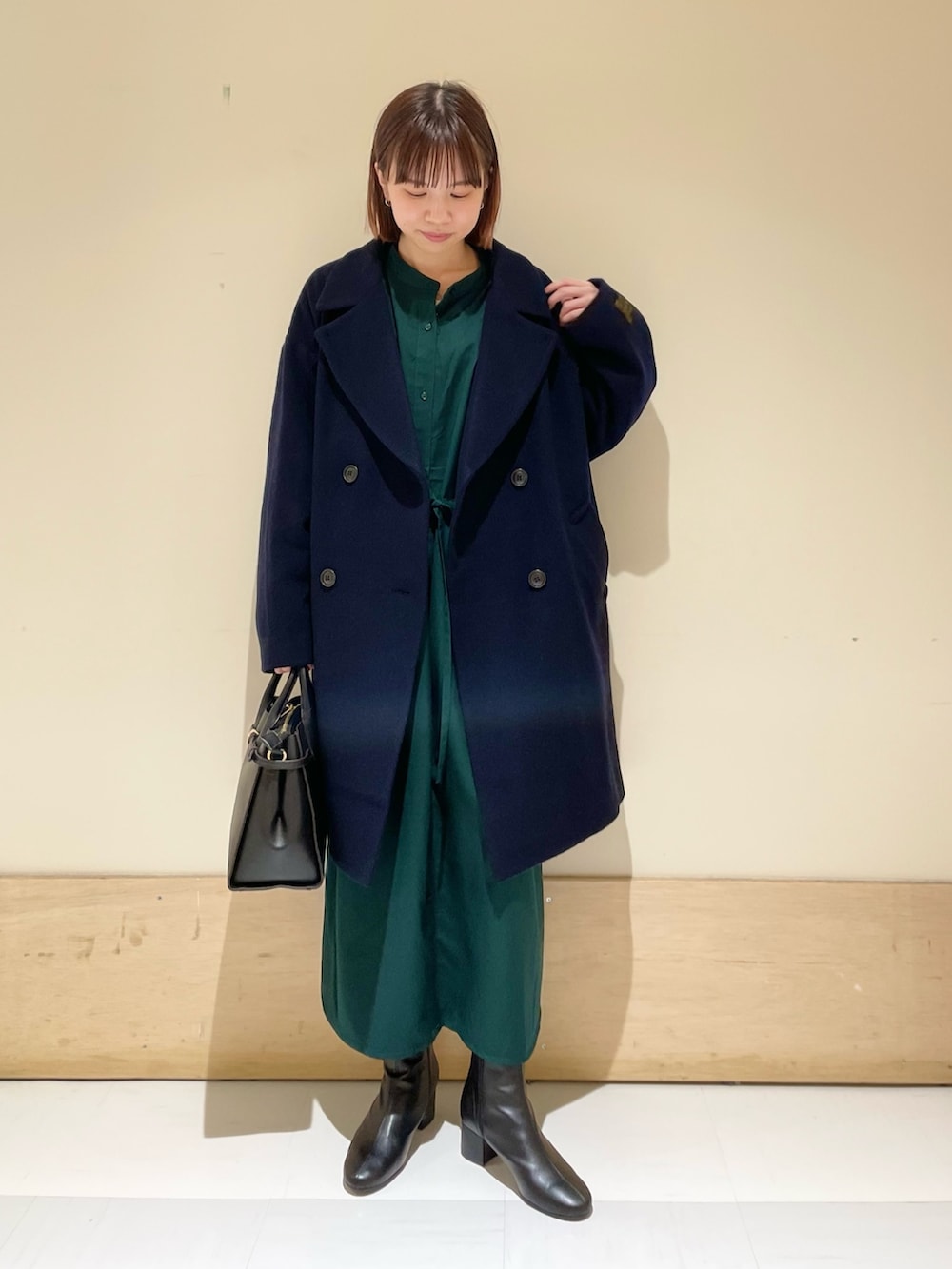 グリーン系のワンピース、ブルー系のピーコート、ブラック系のブーツを着用したレディースの冬コーディネートの3枚目の写真