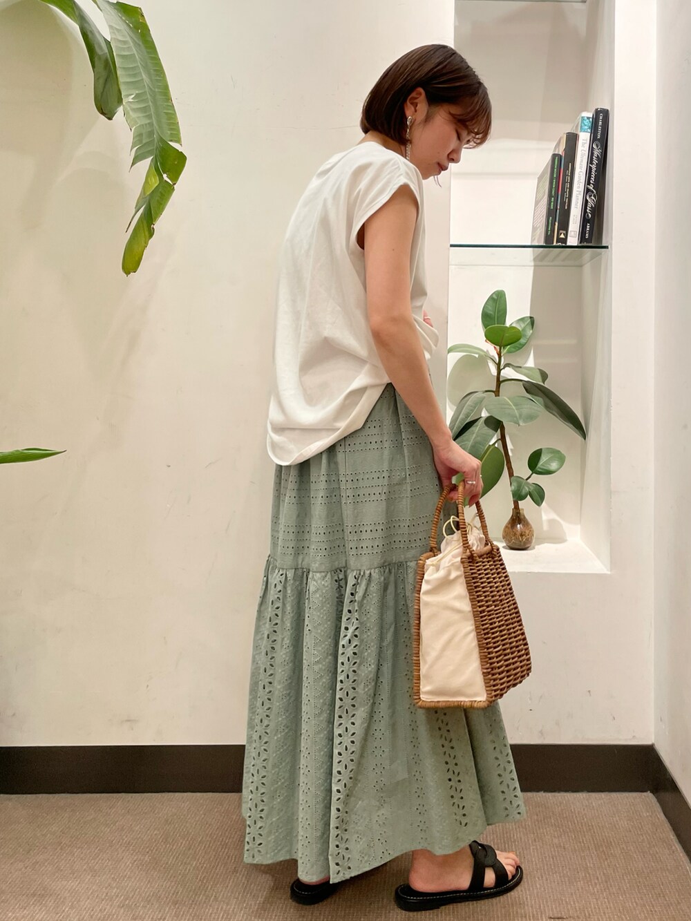 ホワイト系のハンドバッグ、ホワイト系のTシャツ/カットソー、グリーン系のスカートを着用したレディースの夏コーディネートの3枚目の写真