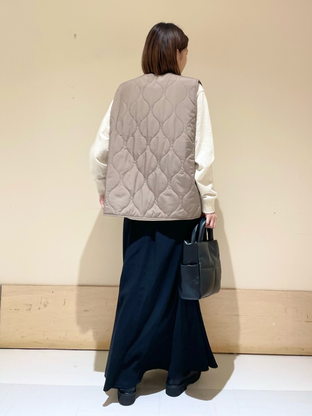 ブラック系のスカート、ブラック系のブーツ、ブラウン系のダウンベストを着用したレディースの秋コーディネートの6枚目の写真