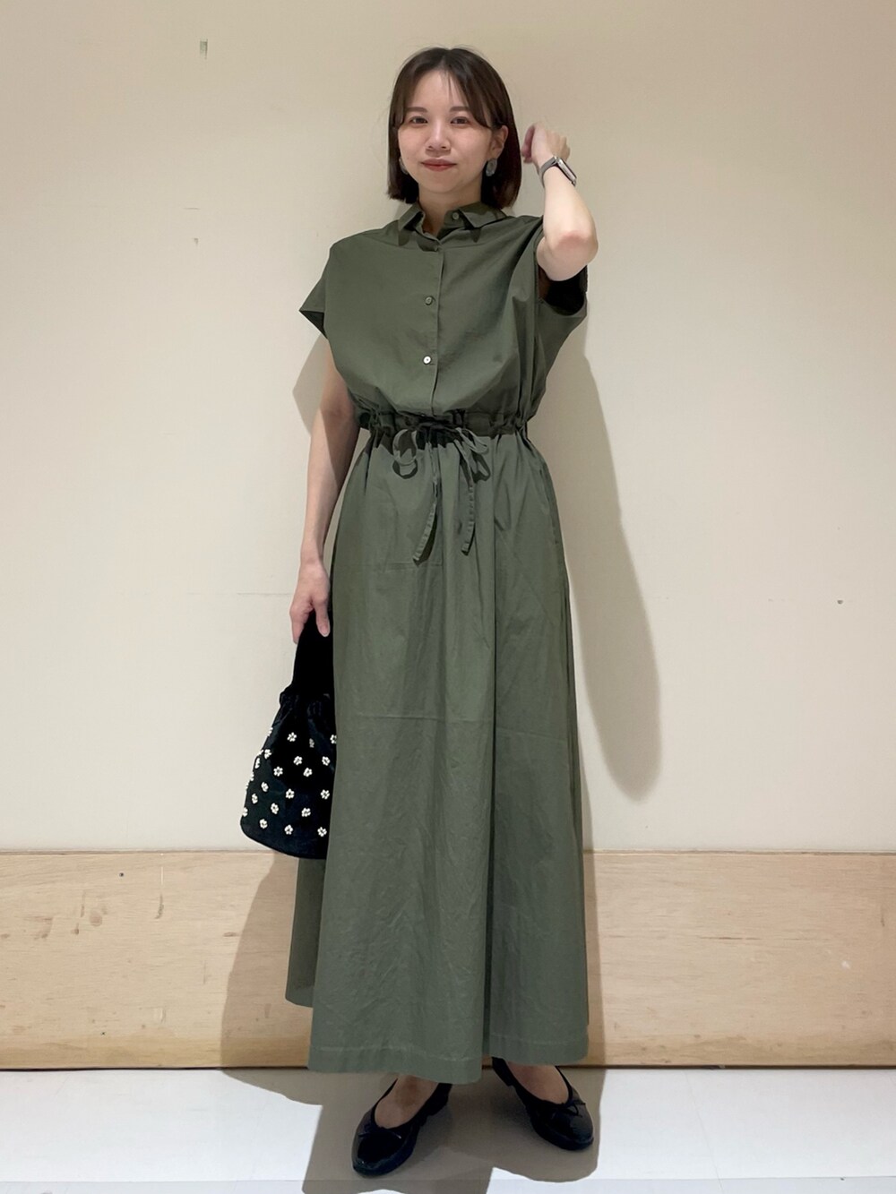 ブラック系のパンプス、ベージュ系のハンドバッグ、グリーン系のワンピースを着用したレディースの夏コーディネートの3枚目の写真