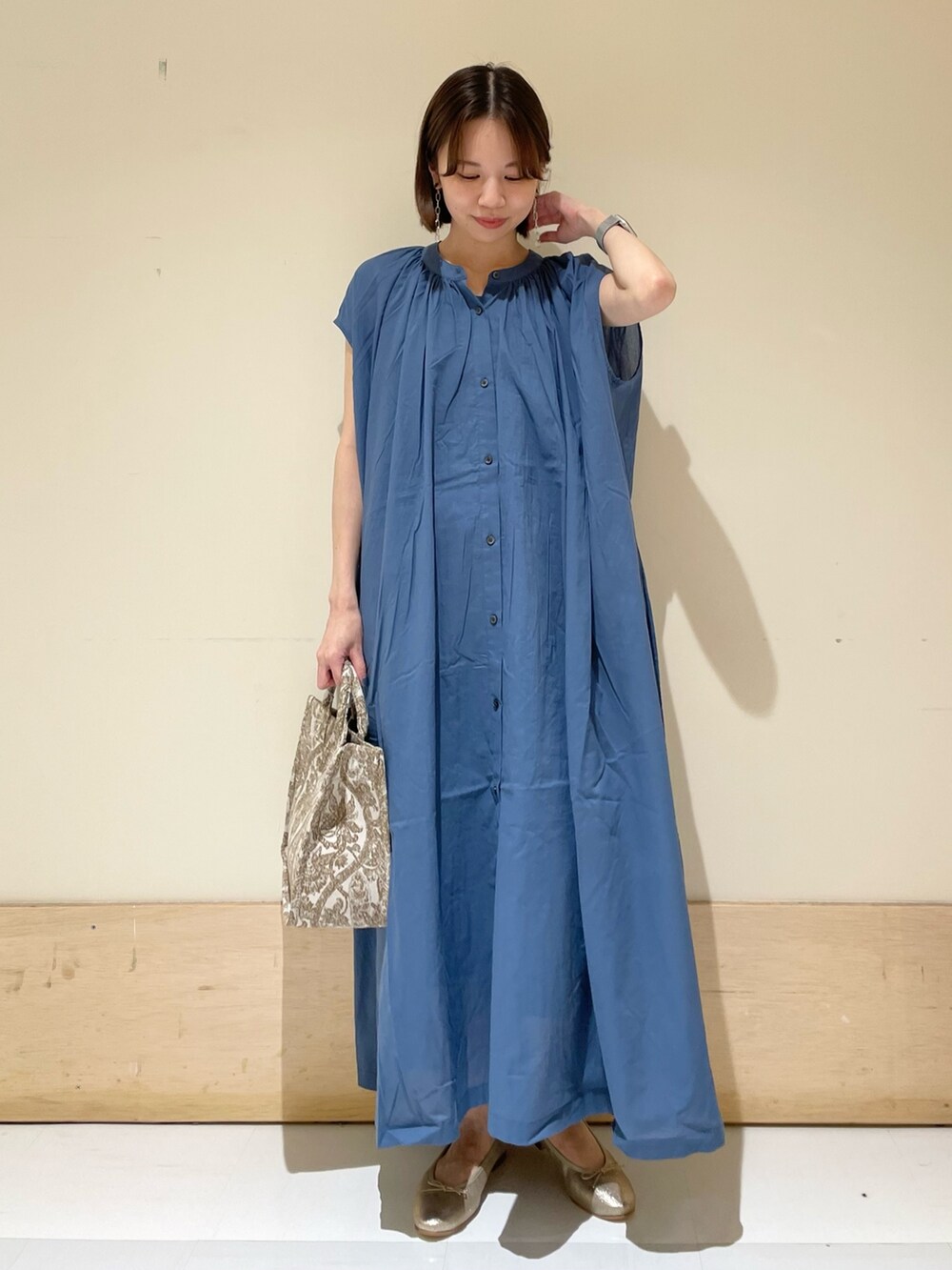 ブルー系のワンピース、ベージュ系のトートバッグ、ゴールド系のパンプスを着用したレディースの夏コーディネートの2枚目の写真