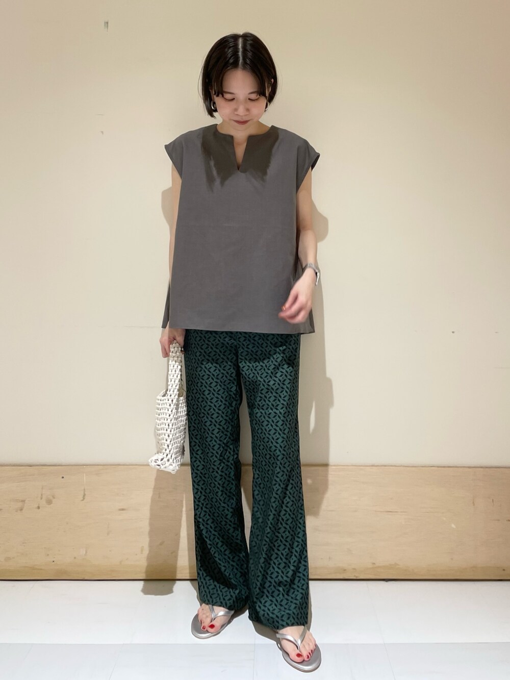 グレー系のシャツ/ブラウス、ホワイト系のハンドバッグ、シルバー系のサンダルを着用したレディースの夏コーディネートの4枚目の写真