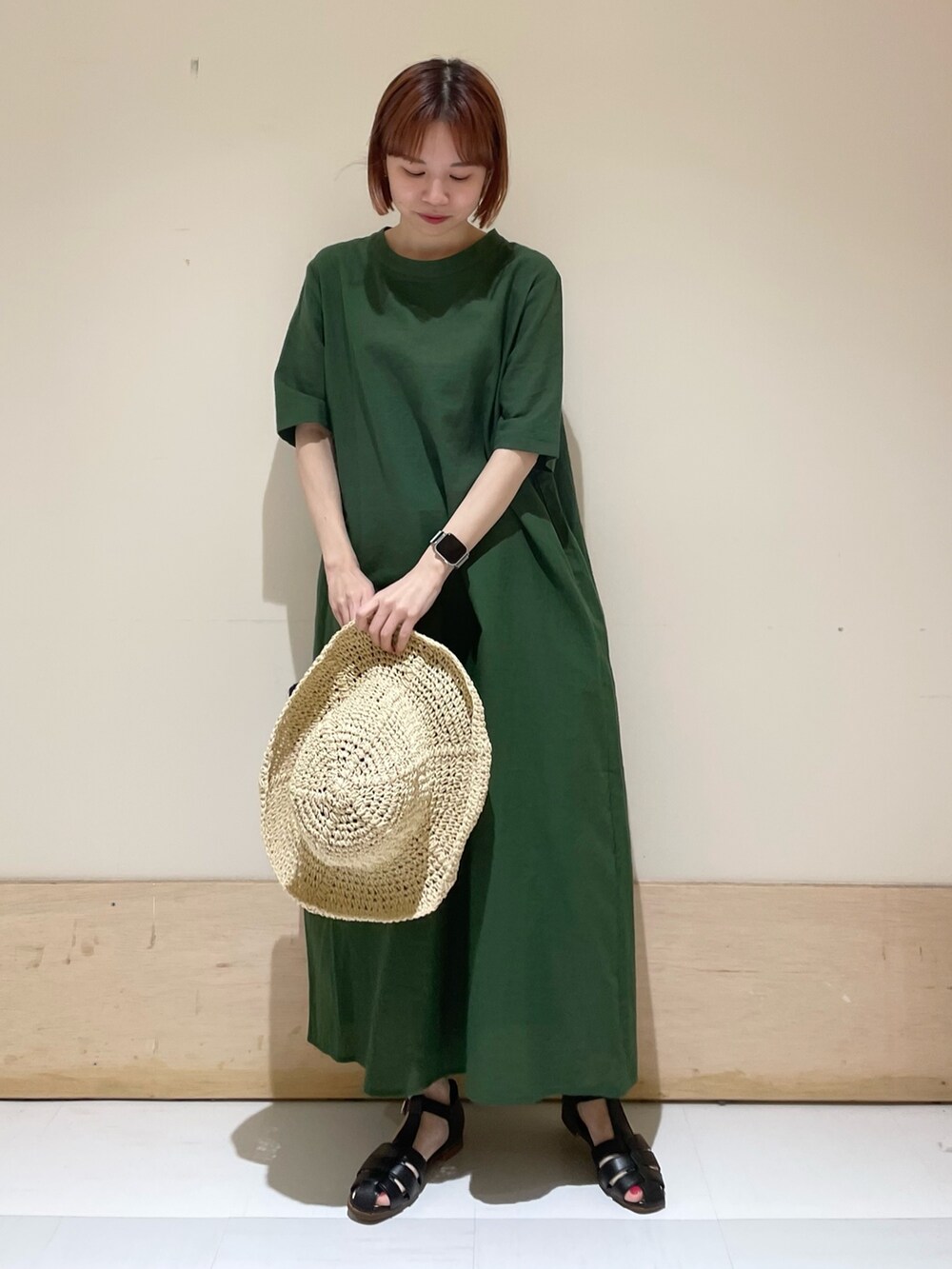 グリーン系のワンピース、ブラック系のサンダル、ブラック系のハンドバッグを着用したレディースの春コーディネートの2枚目の写真