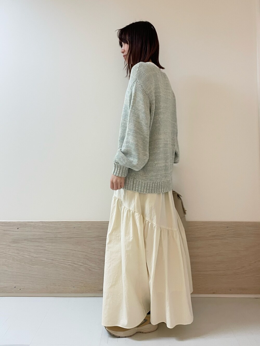 グリーン系のニット/セーター、ホワイト系のスカート、ベージュ系のスニーカーを着用したレディースの春コーディネートの4枚目の写真