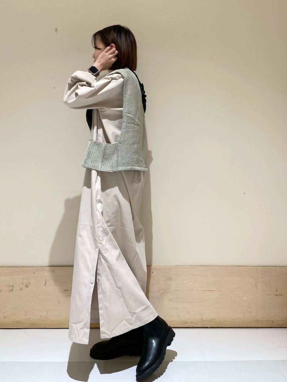 グレー系のワンピース、ブラック系のブーツ、グレー系のベストを着用したレディースの秋コーディネートの4枚目の写真