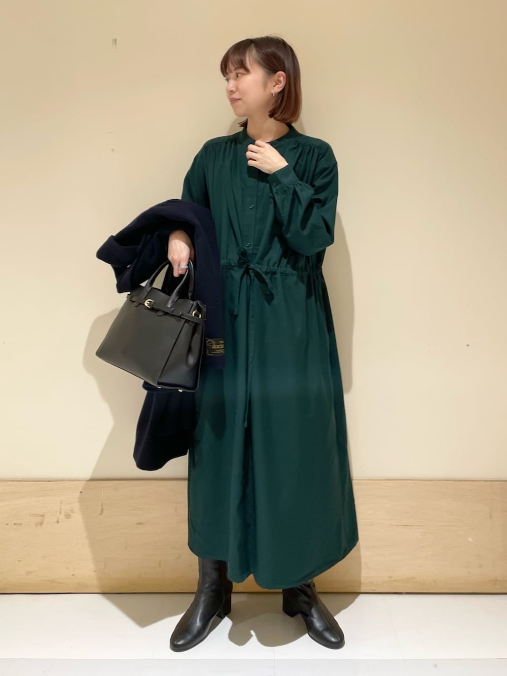 グリーン系のワンピース、ブルー系のピーコート、ブラック系のブーツを着用したレディースの冬コーディネートの8枚目の写真
