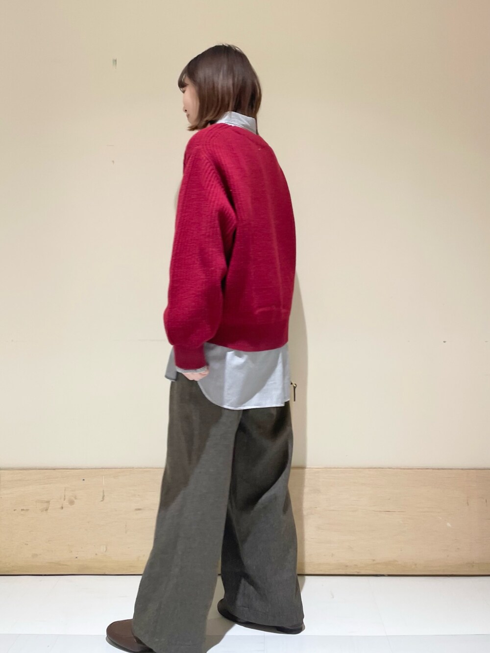 レッド系のニット/セーター、ブラウン系のその他パンツ、ブルー系のシャツ/ブラウスを着用したレディースの冬コーディネートの4枚目の写真