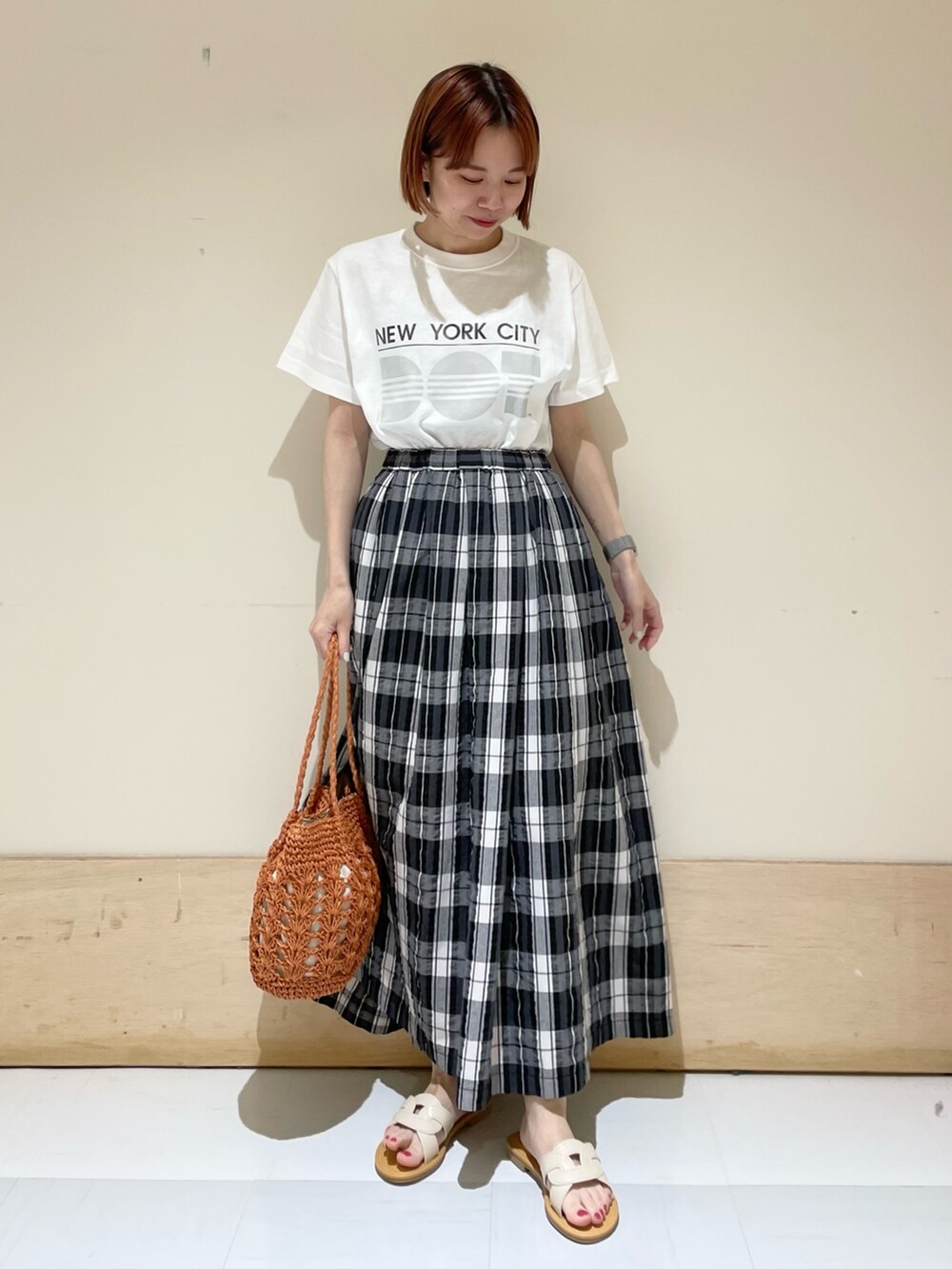 ブラック系のスカート、グレー系のTシャツ/カットソー、ブラウン系のかごバッグを着用したレディースの春コーディネートの4枚目の写真