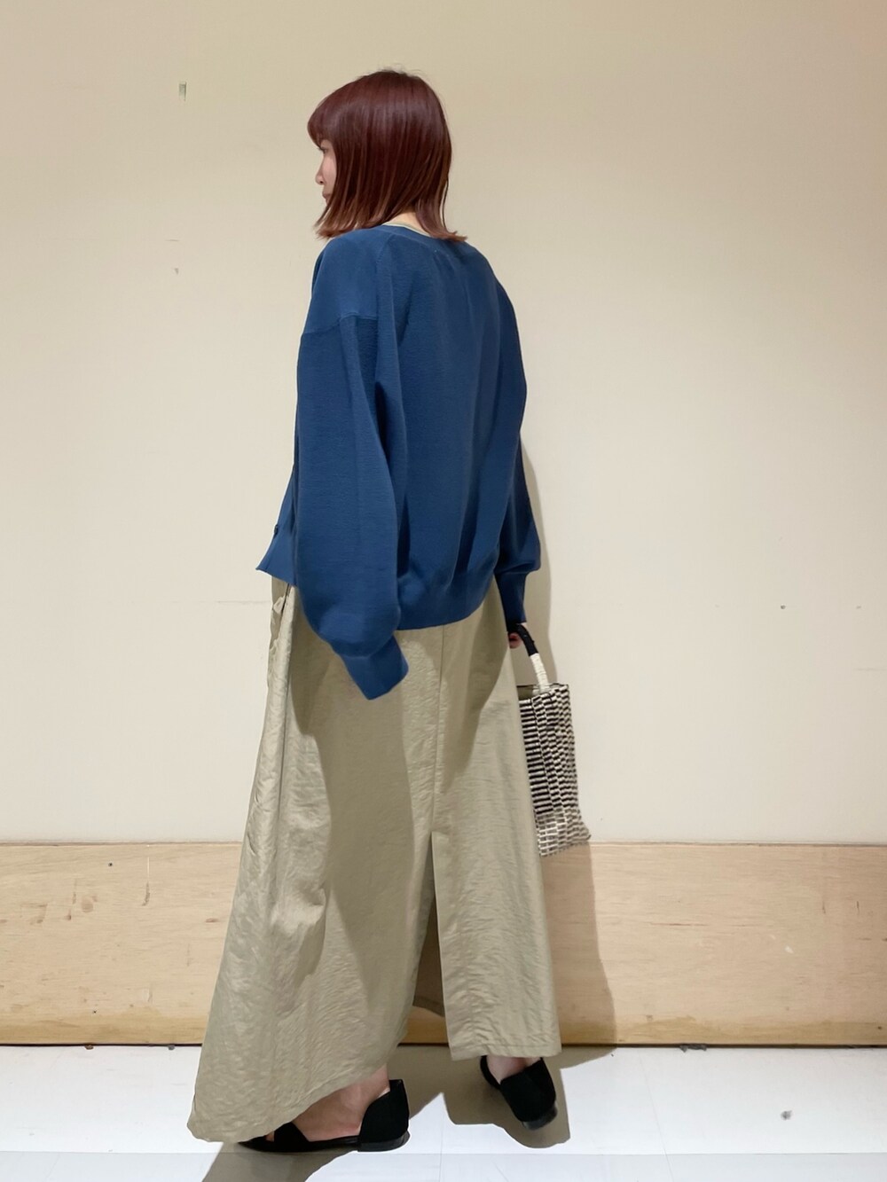 ベージュ系のワンピース、ブルー系のニット/セーター、ブラック系のショルダーバッグを着用したレディースの春コーディネートの5枚目の写真