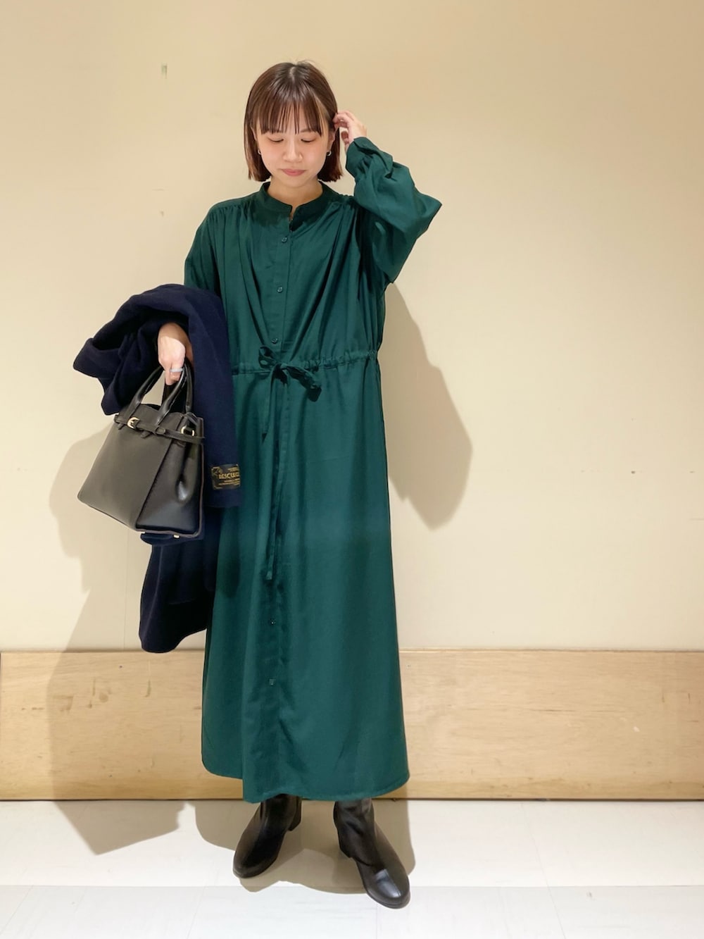 グリーン系のワンピース、ブルー系のピーコート、ブラック系のブーツを着用したレディースの冬コーディネートの7枚目の写真