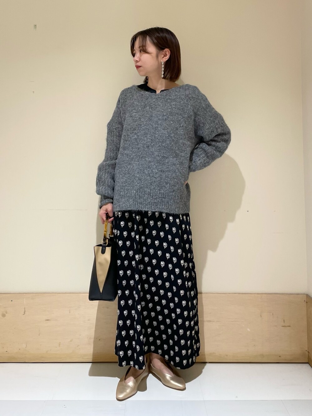 グレー系のニット/セーター、ブラック系のワンピース、ブラック系のハンドバッグを着用したレディースの秋コーディネートの3枚目の写真