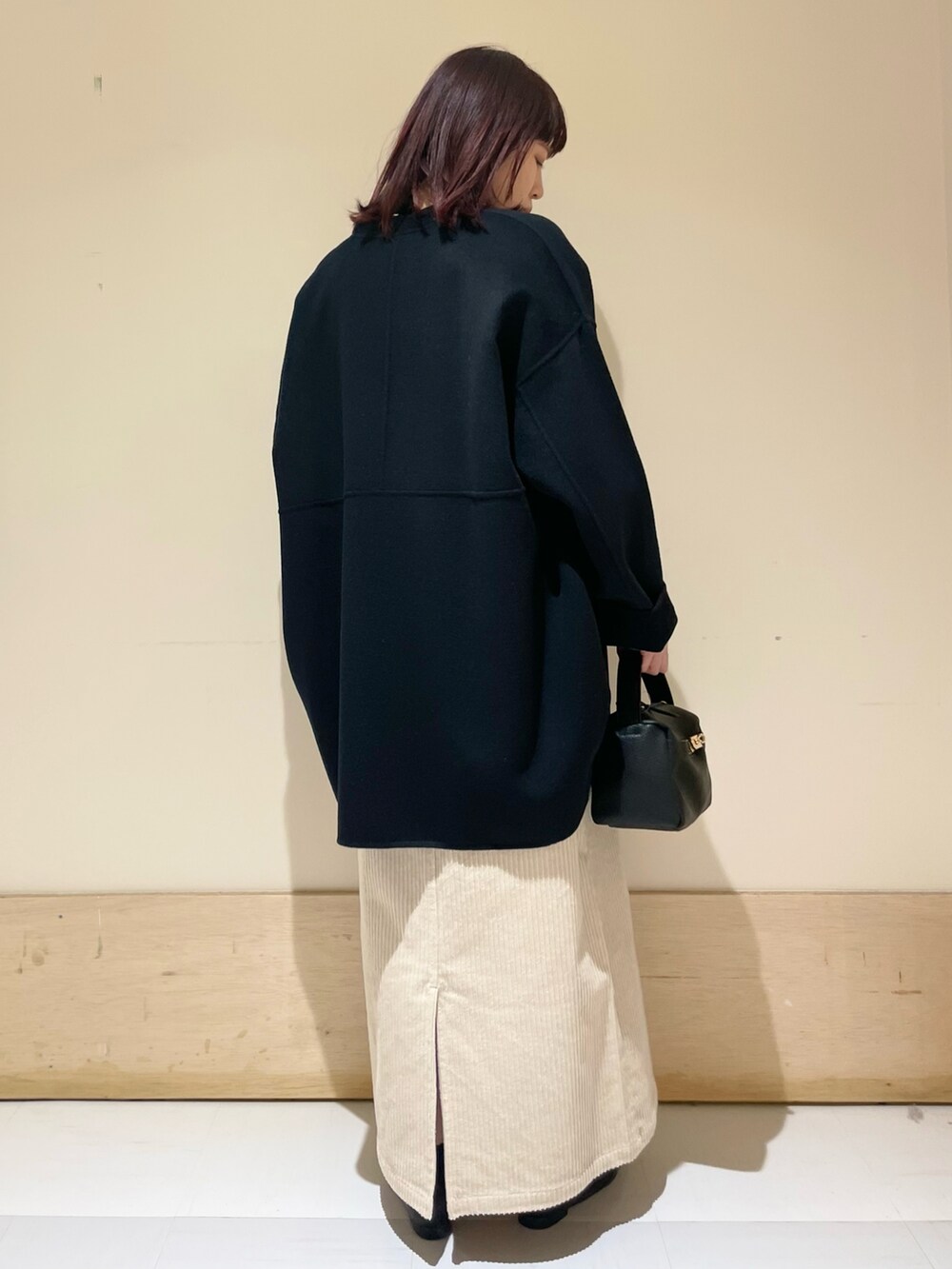 ブラウン系のスウェット、ブラック系のその他アウター、ホワイト系のスカートを着用したレディースの冬コーディネートの4枚目の写真