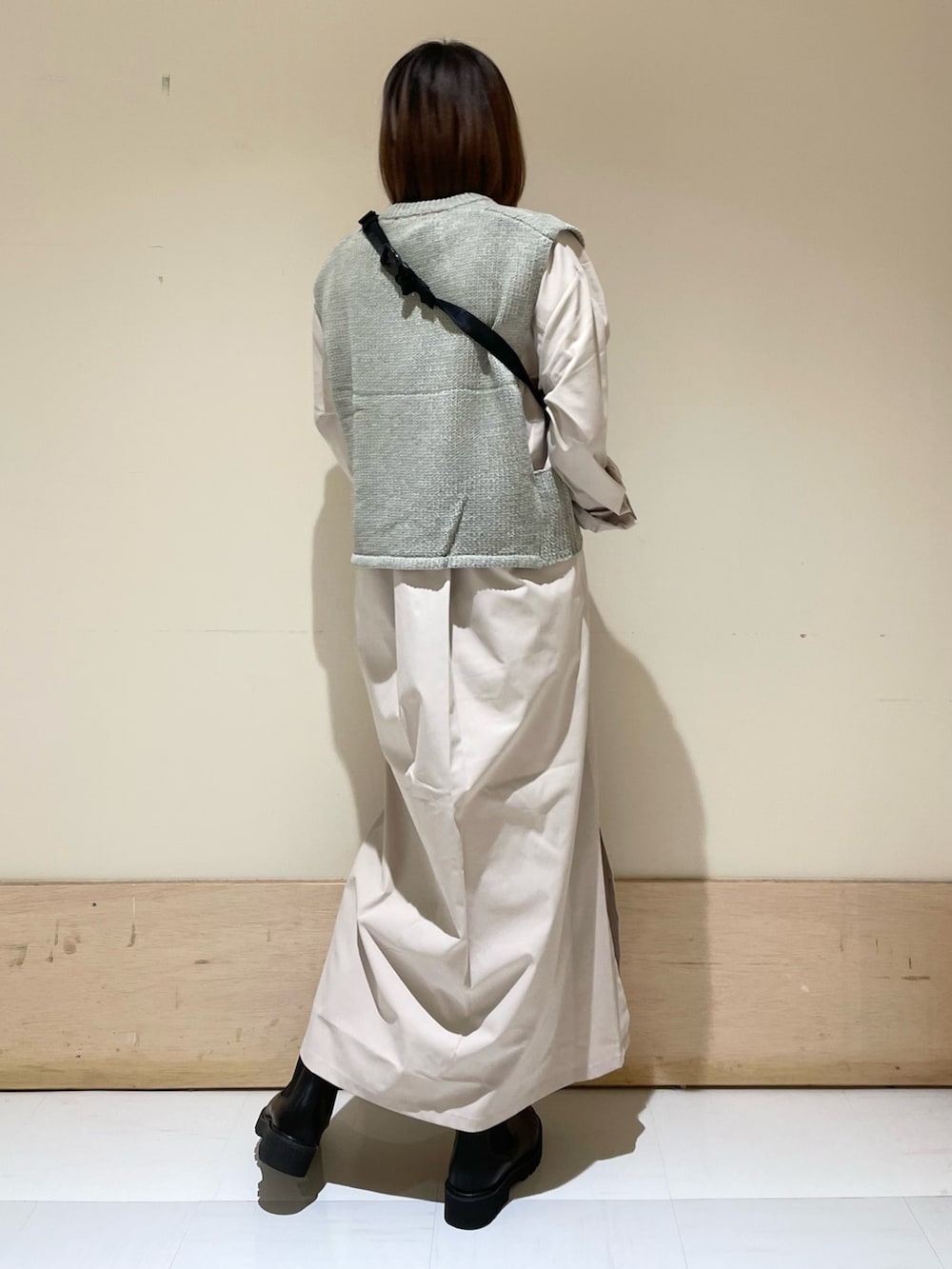 グレー系のワンピース、ブラック系のブーツ、グレー系のベストを着用したレディースの秋コーディネートの6枚目の写真