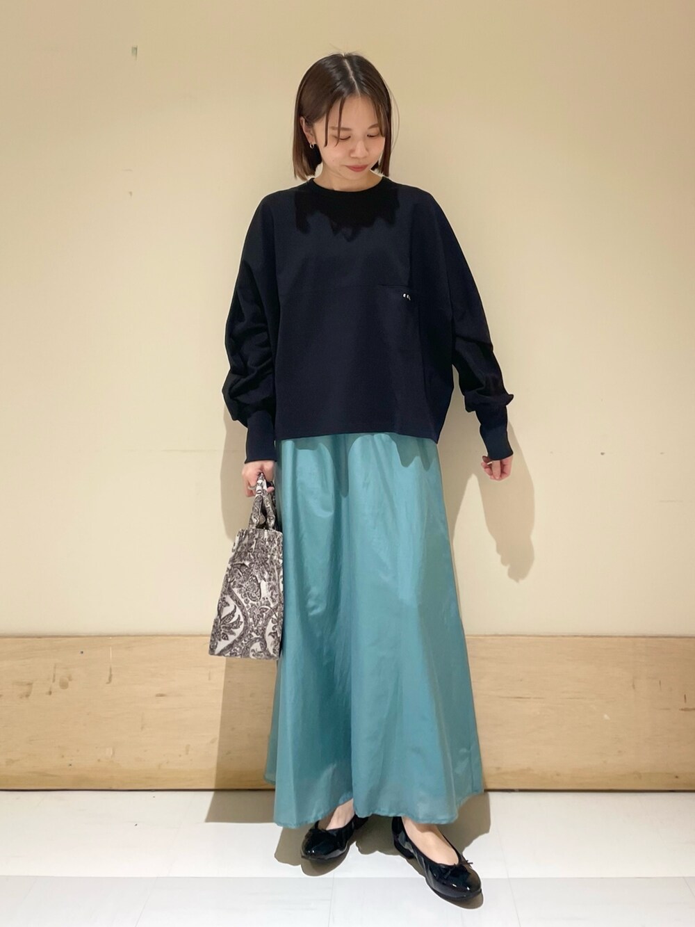 ブラック系のTシャツ/カットソー、グリーン系のスカート、ブラウン系のトートバッグを着用したレディースの秋コーディネートの4枚目の写真