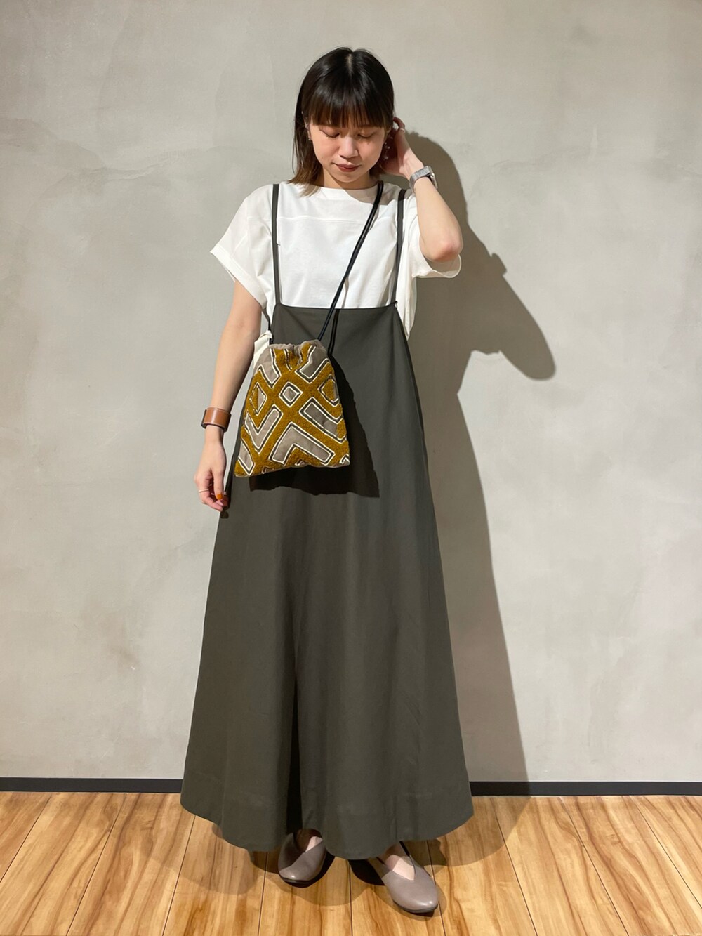 グリーン系のスカート、ホワイト系のTシャツ/カットソー、ブラック系のショルダーバッグを着用したレディースの秋コーディネートの2枚目の写真