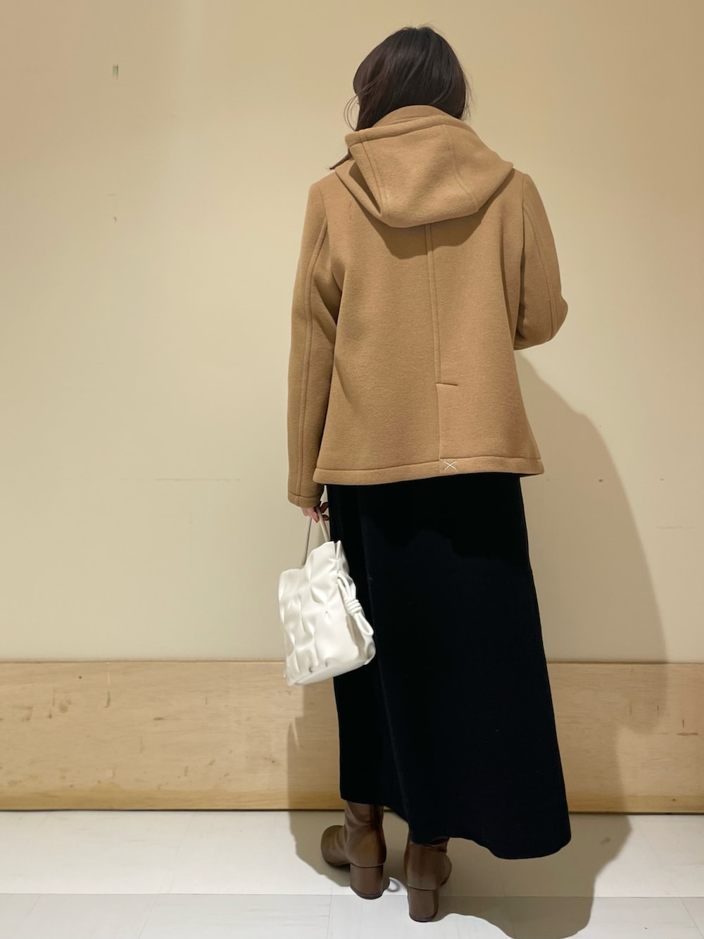 イエロー系のピーコート、ブラック系のワンピース、ブラウン系のブーツを着用したレディースの冬コーディネートの4枚目の写真