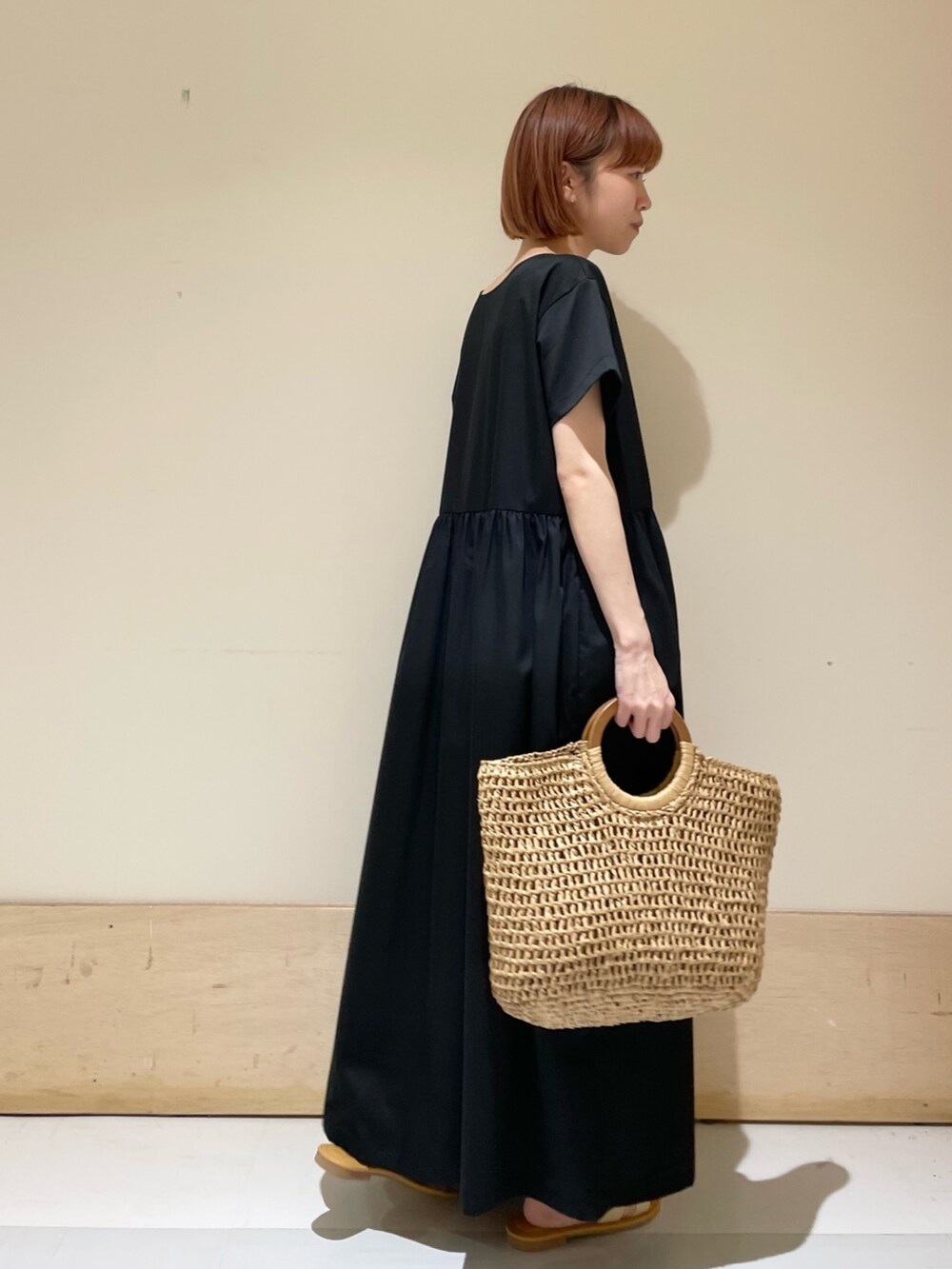 ホワイト系のサンダル、ベージュ系のかごバッグ、ブラック系のワンピースを着用したレディースの春コーディネートの6枚目の写真