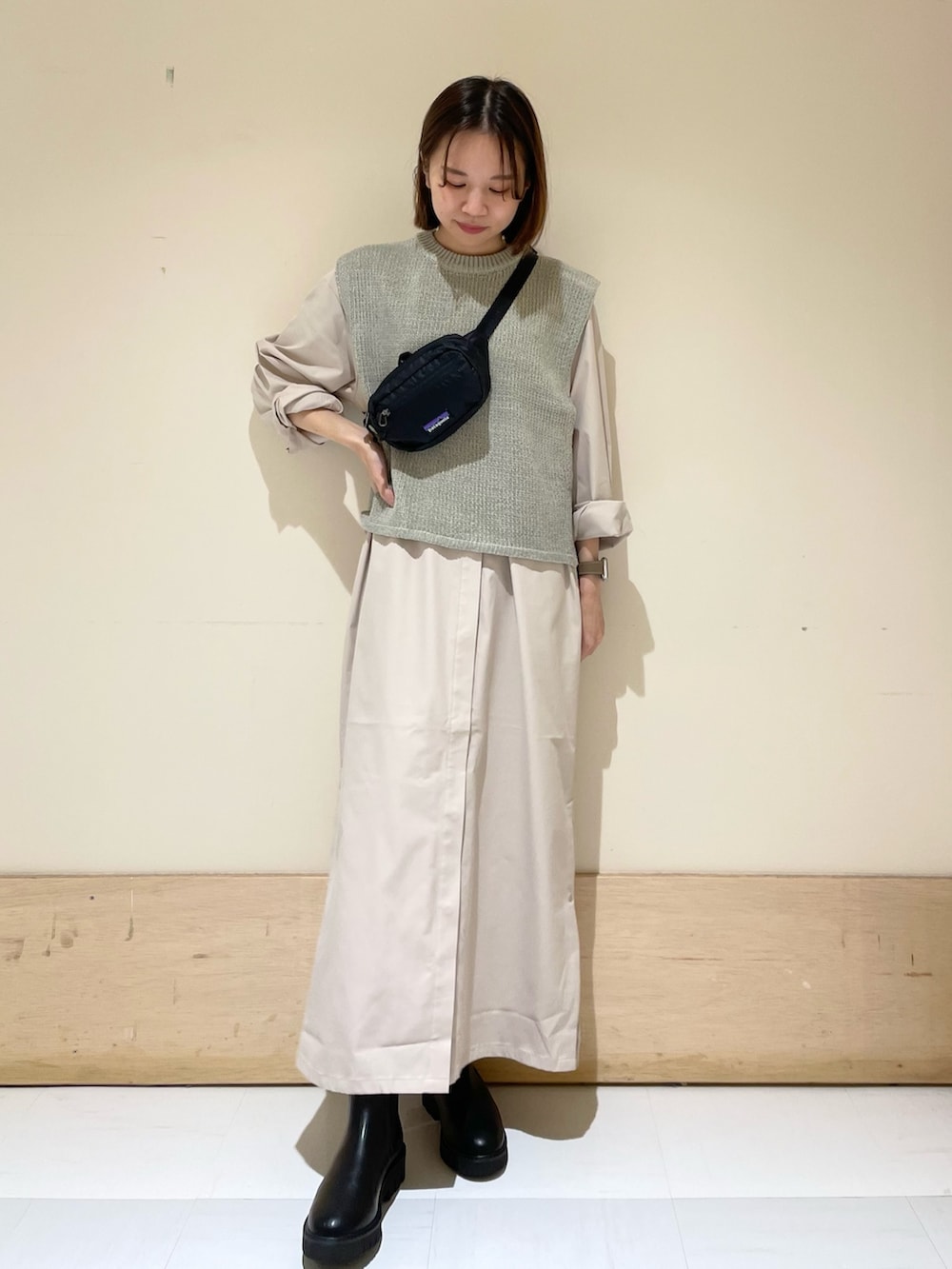 グレー系のワンピース、ブラック系のブーツ、グレー系のベストを着用したレディースの秋コーディネートの3枚目の写真