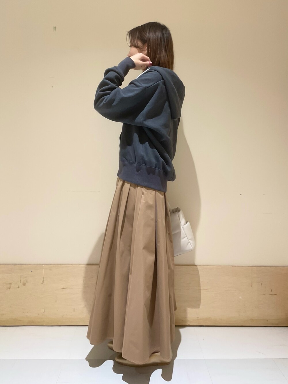 ゴールド系のパンプス、ホワイト系のトートバッグ、ベージュ系のスカートを着用したレディースの秋コーディネートの3枚目の写真