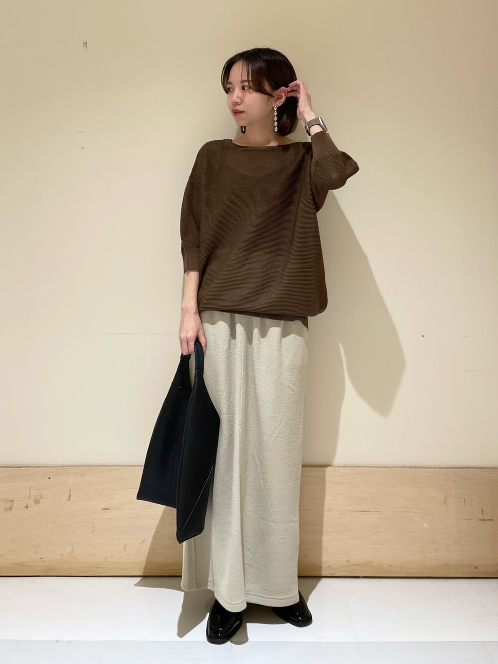 ブラウン系のニット/セーター、ベージュ系のスカート、ブラック系のドレスシューズを着用したレディースの秋コーディネートの2枚目の写真