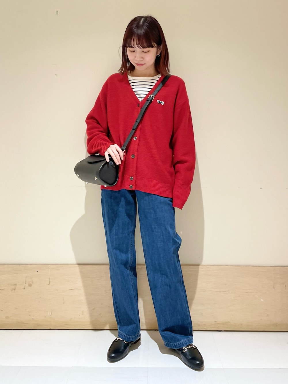 ブラック系のショルダーバッグ、レッド系のカーディガン/ボレロ、ホワイト系のTシャツ/カットソーを着用したレディースの冬コーディネートの3枚目の写真