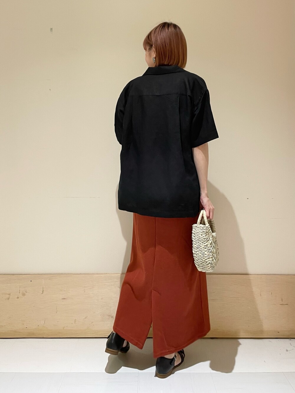 オレンジ系のワンピース、グレー系のかごバッグ、ブラック系のシャツ/ブラウスを着用したレディースの春コーディネートの6枚目の写真