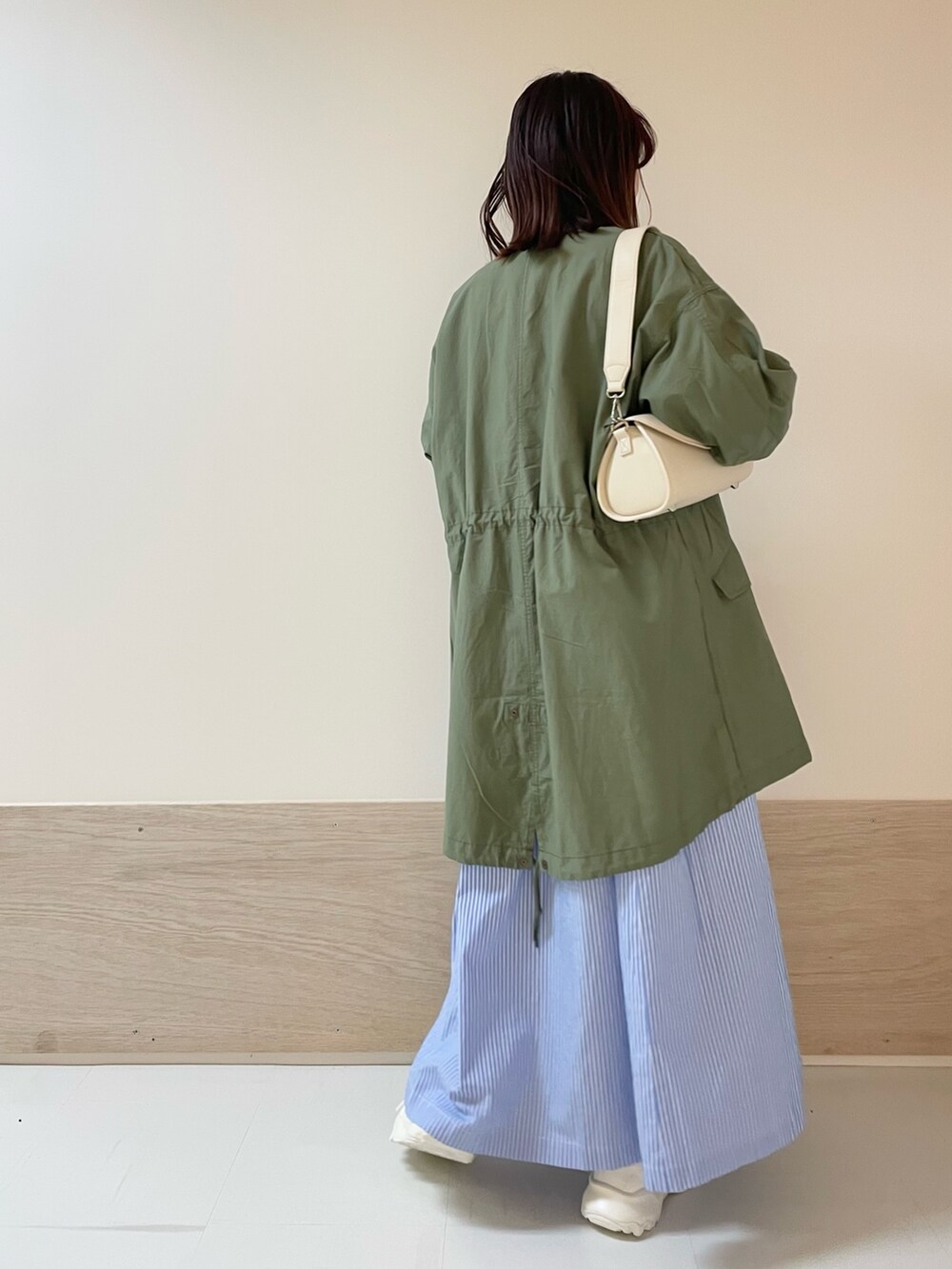 ホワイト系のショルダーバッグ、グリーン系のモッズコート、ブルー系のワンピースを着用したレディースの春コーディネートの6枚目の写真