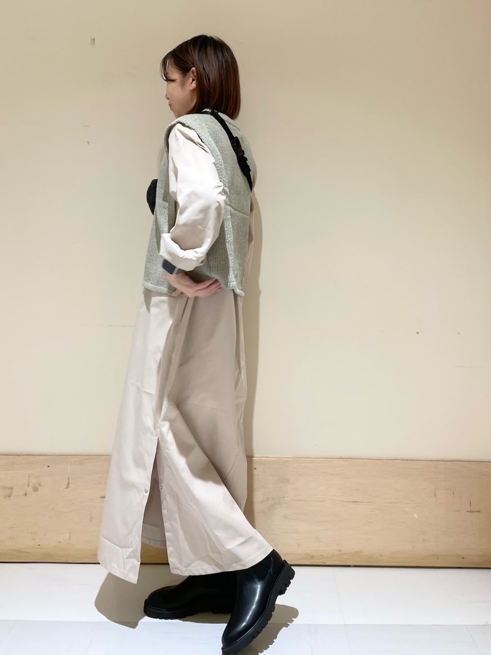 グレー系のワンピース、ブラック系のブーツ、グレー系のベストを着用したレディースの秋コーディネートの5枚目の写真