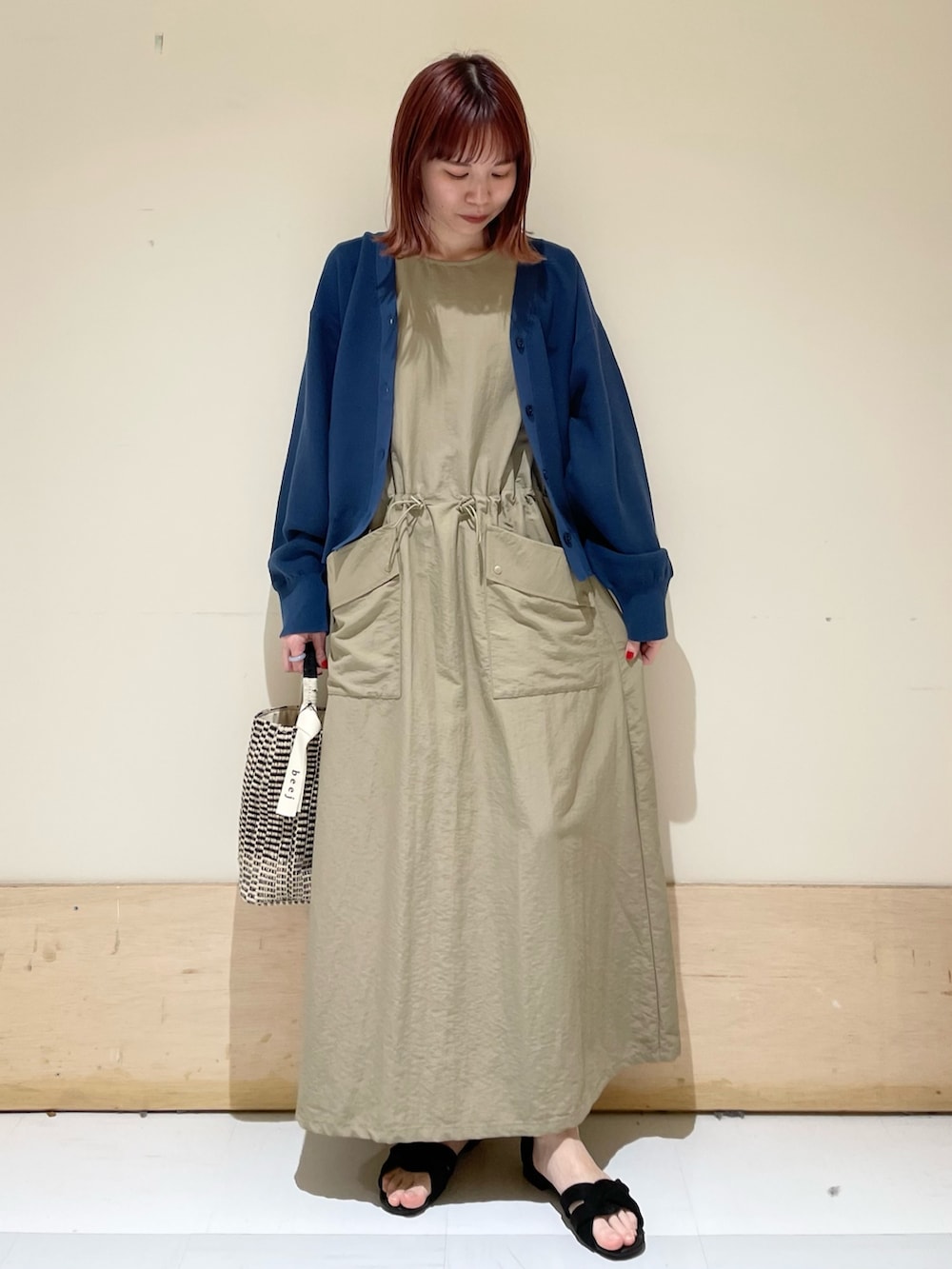 ベージュ系のワンピース、ブルー系のニット/セーター、ブラック系のショルダーバッグを着用したレディースの春コーディネートの2枚目の写真