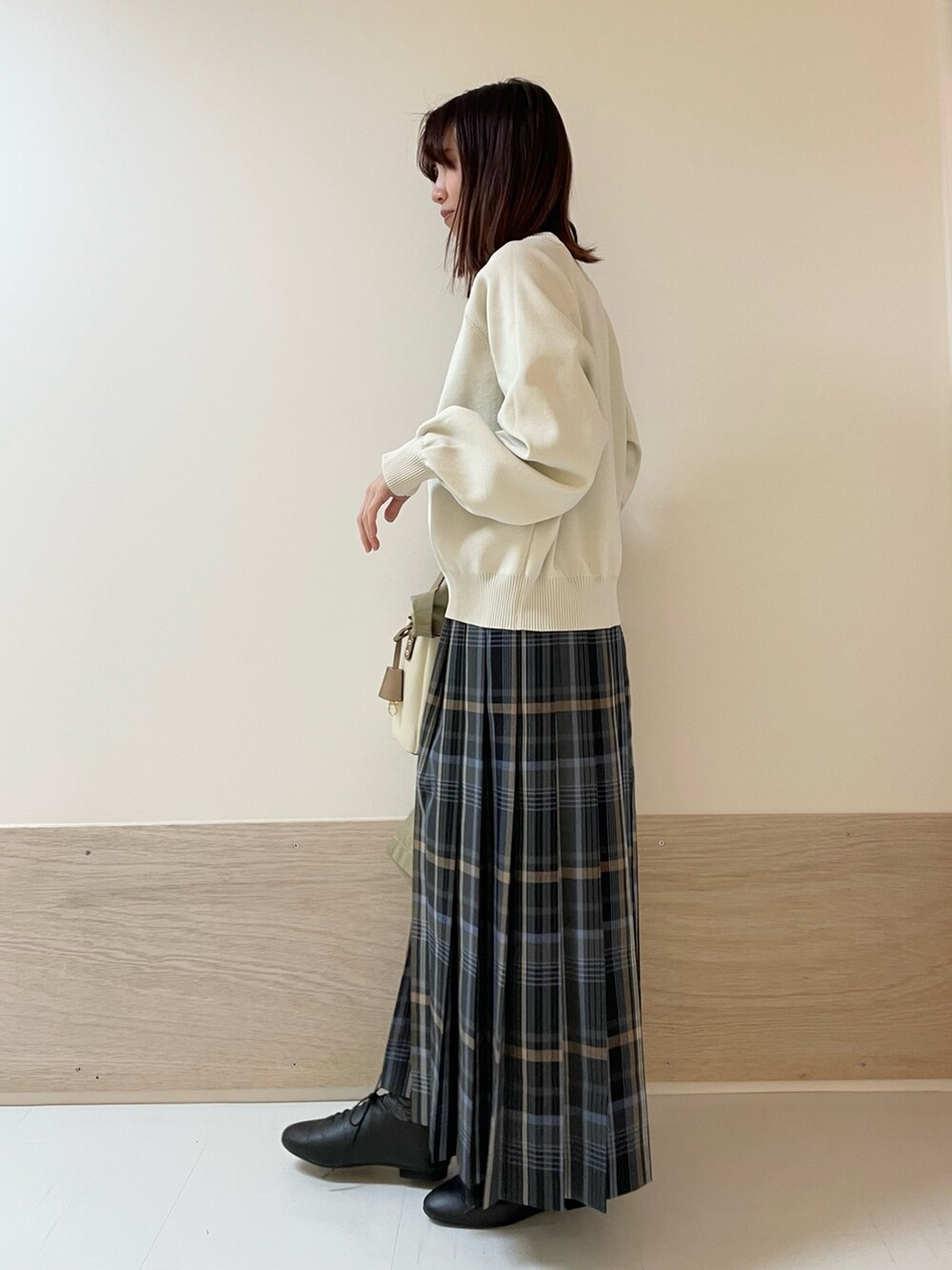 グレー系のスカート、ホワイト系のニット/セーター、ベージュ系のその他アウターを着用したレディースの春コーディネートの2枚目の写真