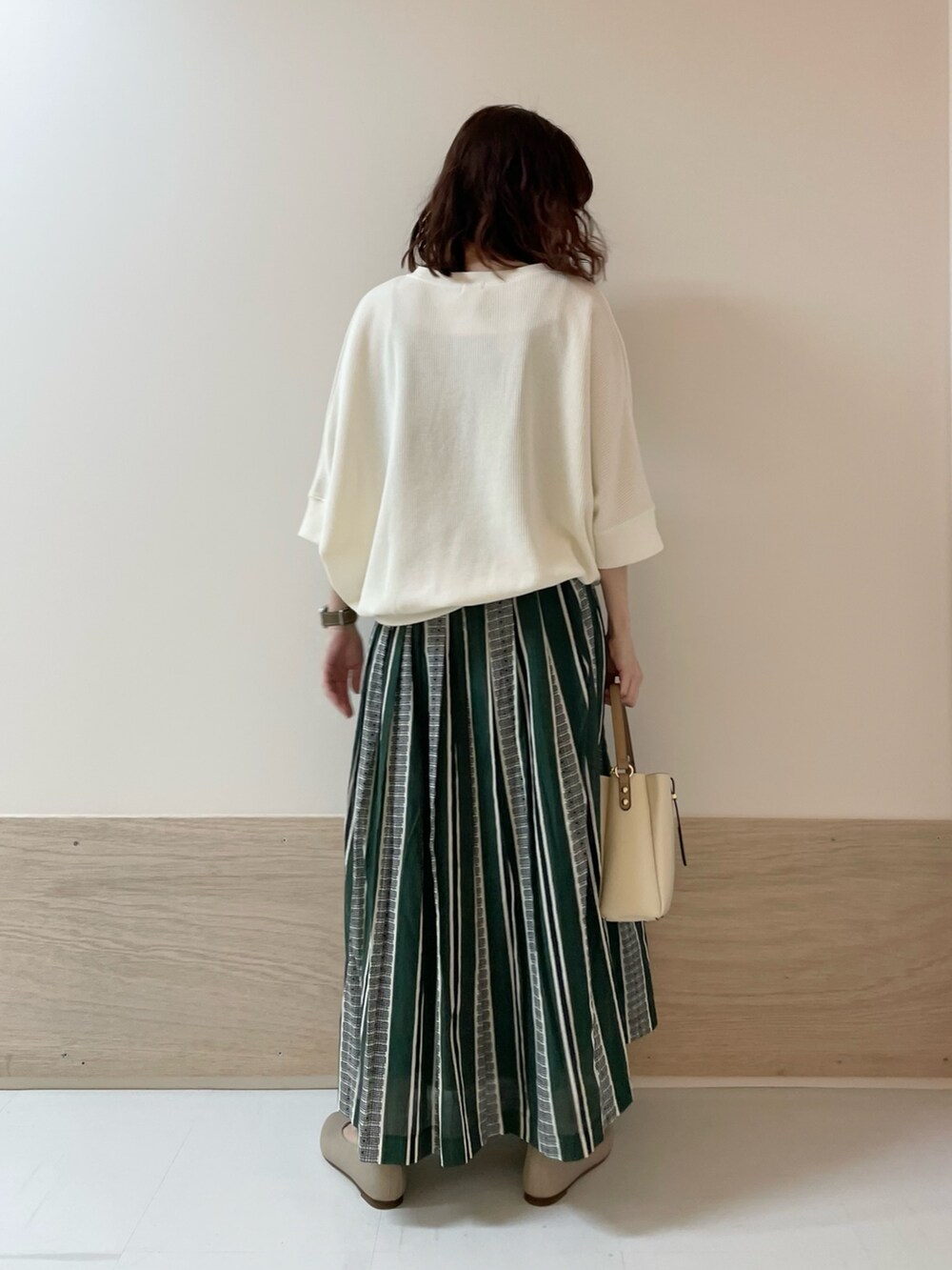 ホワイト系のTシャツ/カットソー、グリーン系のスカート、ベージュ系のパンプスを着用したレディースの春コーディネートの7枚目の写真