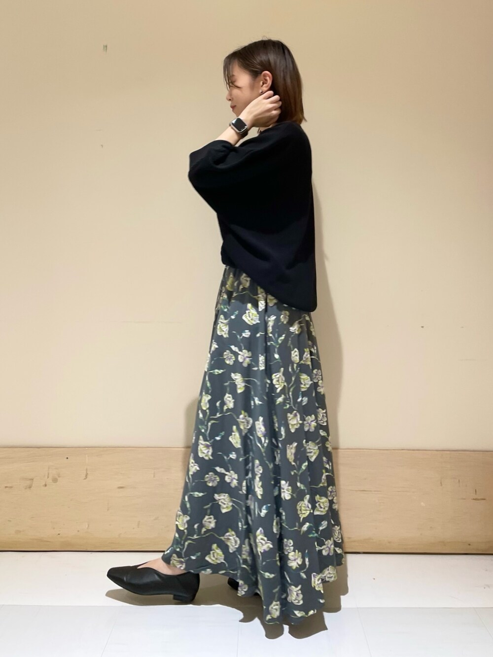 グレー系のスカート、ホワイト系のショルダーバッグ、ブラック系のパンプスを着用したレディースの秋コーディネートの5枚目の写真