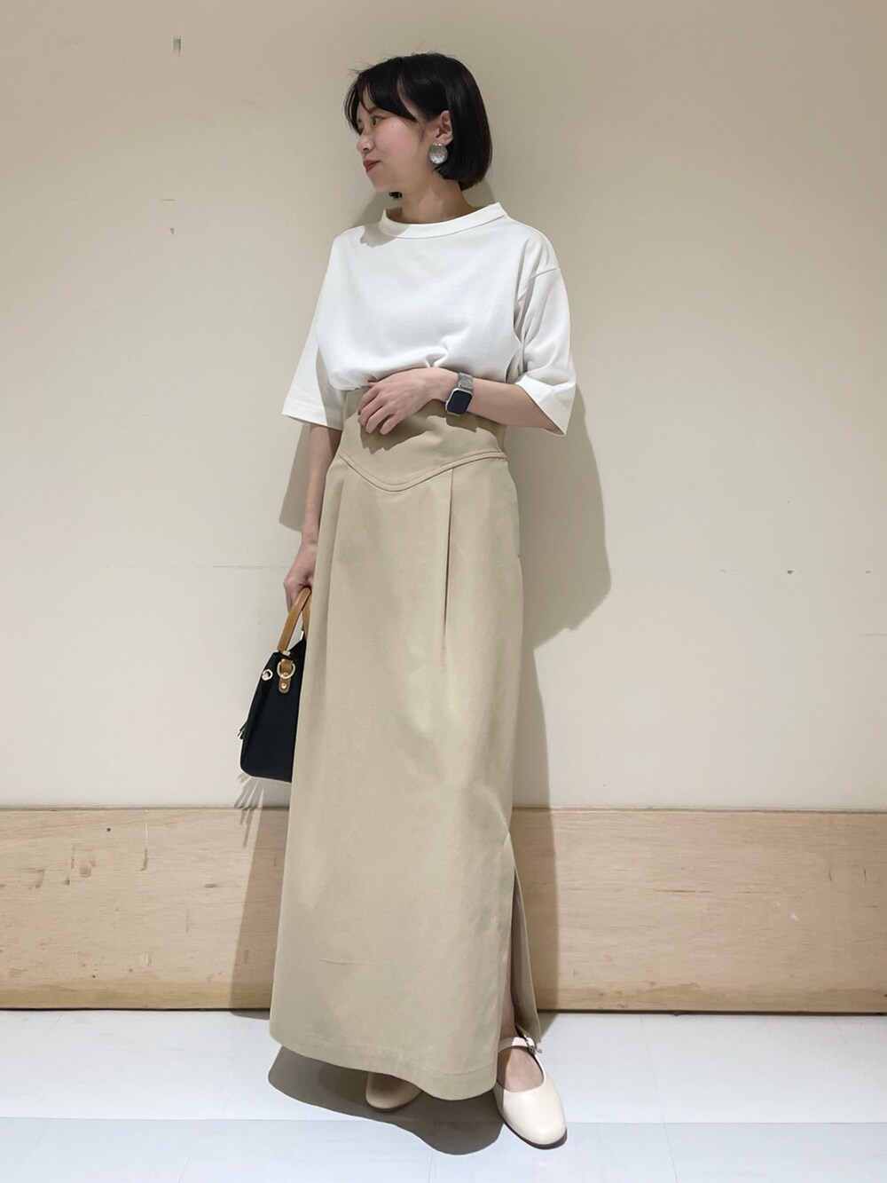 ホワイト系のTシャツ/カットソー、ブラック系のトートバッグ、ベージュ系のスカートを着用したレディースの夏コーディネートの2枚目の写真