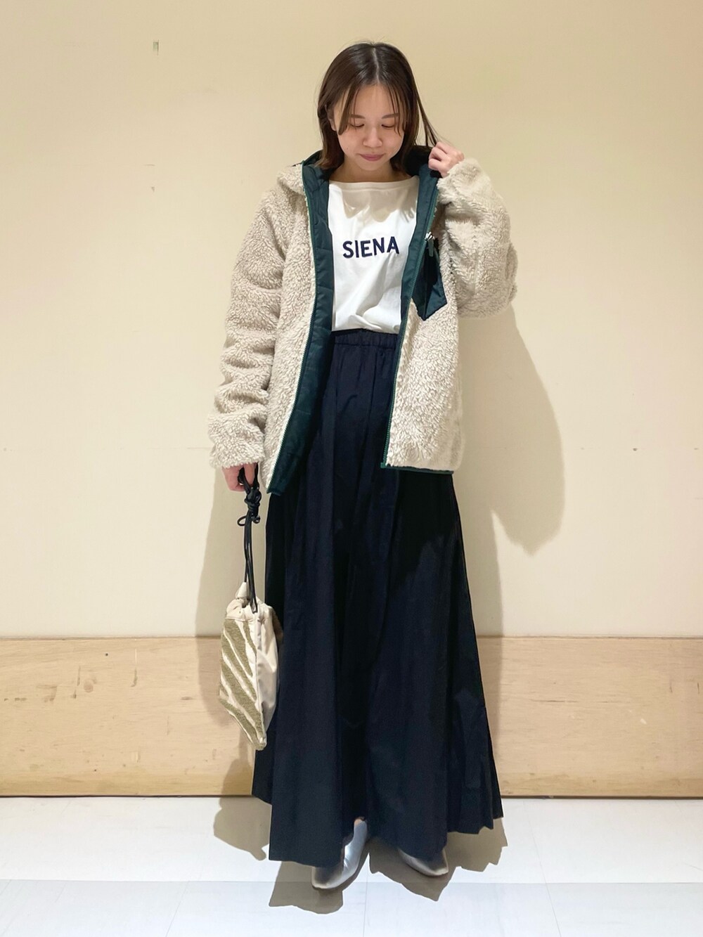 シルバー系のパンプス、ブルー系のTシャツ/カットソー、ベージュ系のハンドバッグを着用したレディースの秋コーディネートの3枚目の写真