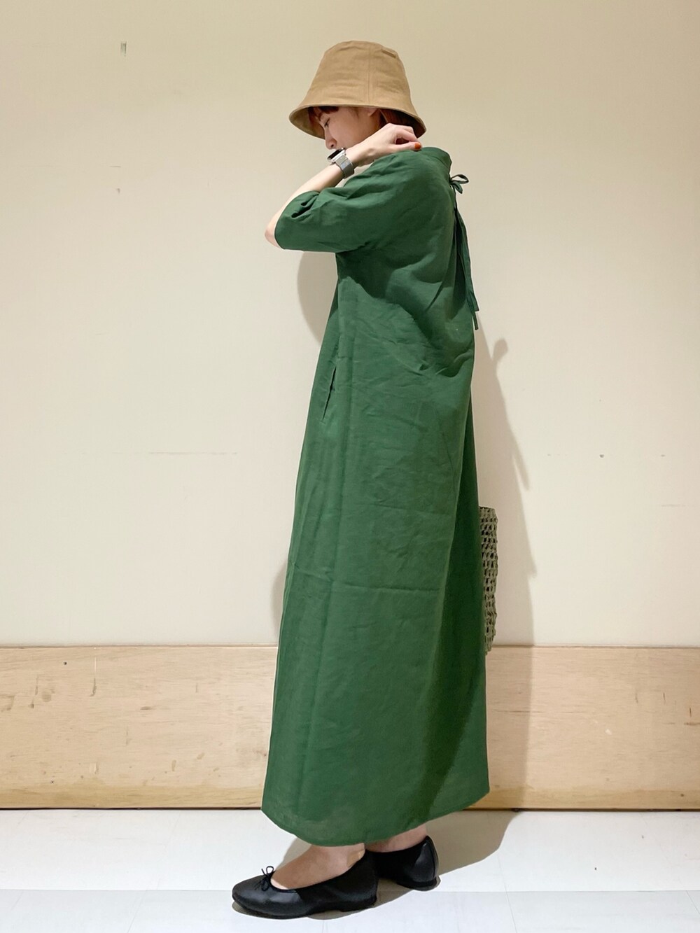 グリーン系のワンピース、ブラック系のバレエシューズ、グリーン系のかごバッグを着用したレディースの春コーディネートの5枚目の写真