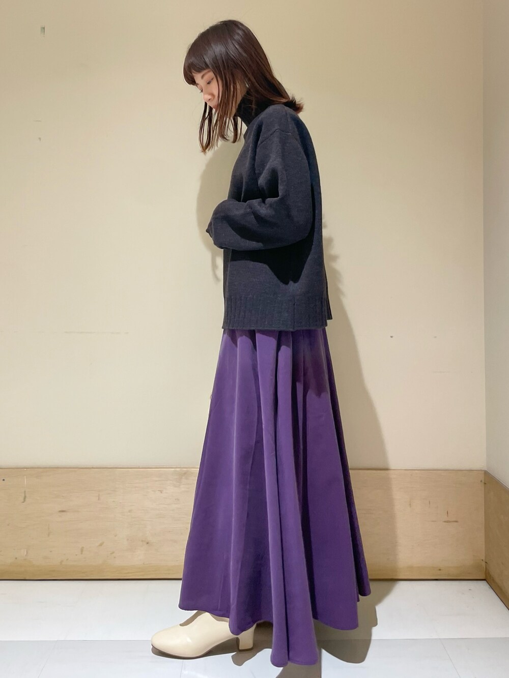 ブルー系のニット/セーター、パープル系のスカート、ホワイト系のハンドバッグを着用したレディースの冬コーディネートの2枚目の写真