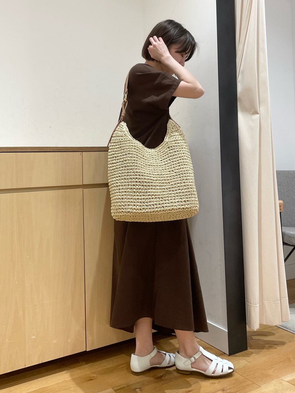 ホワイト系のサンダル、ベージュ系のかごバッグ、ブラウン系のワンピースを着用したレディースの夏コーディネートの3枚目の写真