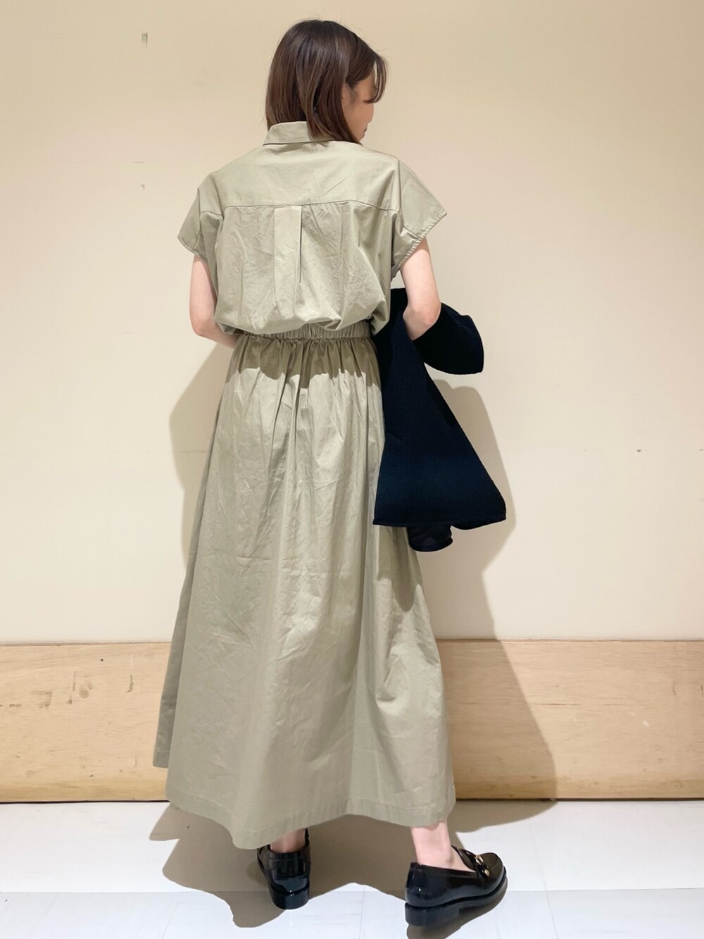 グレー系のショルダーバッグ、ブラック系のノーカラージャケット、ベージュ系のワンピースを着用したレディースの秋コーディネートの8枚目の写真