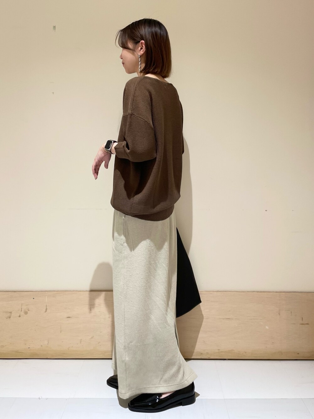 ブラウン系のニット/セーター、ベージュ系のスカート、ブラック系のドレスシューズを着用したレディースの秋コーディネートの5枚目の写真